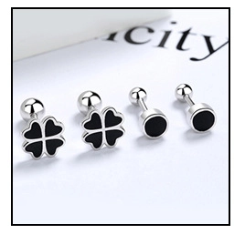 Macro shot of silver stud earrings with black clover and round geometric designs