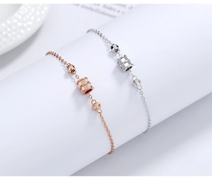 Detail of rose gold and silver cylinder pendants with ribbed texture on sleek chains