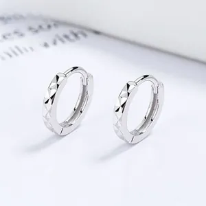 Macro detail of 925 sterling silver hoop earrings with diamond-cut geometric texture