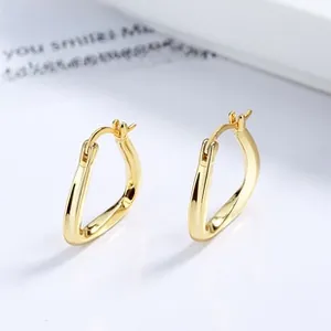 Vue macro de boucles d'oreilles triangulaires dorées avec une finition miroir minimaliste