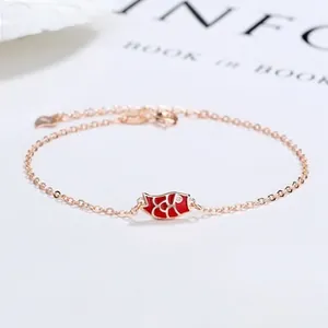 Close-up of a rose gold koi fish charm with red enamel and O-chain on white background