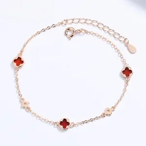 Detail of rose gold clover bracelet with red stones and hollow charms with lobster clasp