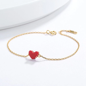 Close-up of a 925 silver gold-plated chain bracelet with a vibrant red heart pendant