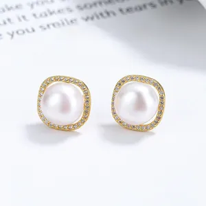 Macro shot of S925 silver pearl stud earrings with gold square frames and small zircons