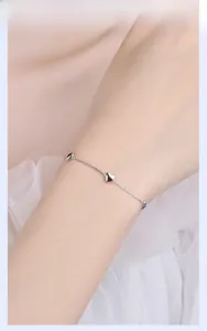 Macro shot of 925 sterling silver minimalist heart charm bracelet on female wrist