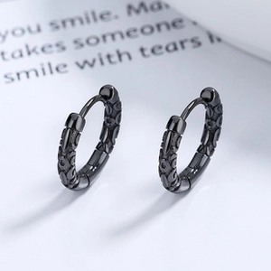 Close-up of black 925 silver hoop earrings with embossed flame patterns on a white card