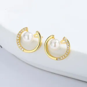 Dettaglio dei orecchini di perle dorate con intarsio di zirconi e design minimalista