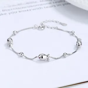 Macro shot of 925 sterling silver fish pendant bracelet with red stone eyes on box chain