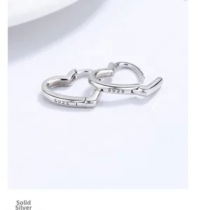 Gros plan du poinçon S925 sur des boucles d'oreilles créoles cœur en argent sterling