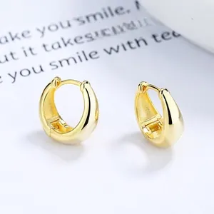 Close-up of teardrop shaped gold earrings on a minimalist white card background