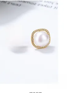 Detail of square gold earrings with white crystals and round freshwater pearl inlays