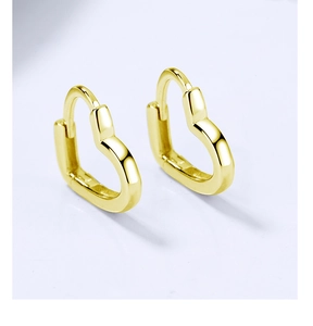 Détail de boucles d'oreilles créoles cœur dorées avec finition métallique polie et lisse