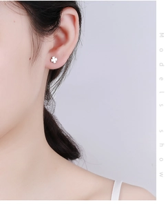 Close-up of minimalist S925 sterling silver four-leaf clover stud earring on model