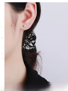 Gros plan d'une puce d'oreille haricot minimaliste en argent 925 portée à l'oreille