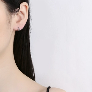 Élégantes boucles d'oreilles couronne en argent 925 portées par un mannequin chic