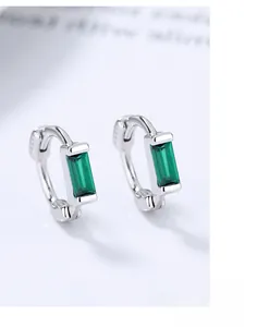 Macro shot of 925 sterling silver hoop earrings with rectangular emerald green gemstones