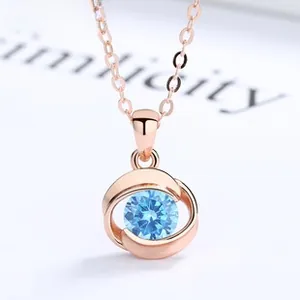 Detailed macro view of a rose gold necklace with a light blue round gemstone pendant