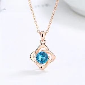 Macro shot of rose gold necklace with blue round gemstone in geometric interlaced pendant