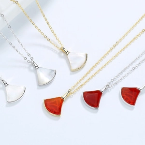 Macro shot of fan-shaped pendants with white shell and red agate on gold silver chains