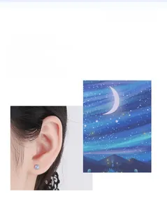 Close-up of a s925 silver moonstone stud earring on ear with a starry background