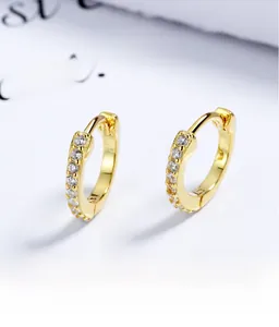 Gros plan de boucles d'oreilles huggie en argent s925 plaqué or 18 carats et zircons