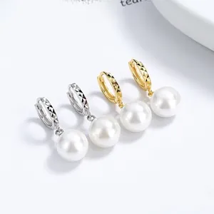 Détail de créoles en argent et or avec surface texturée et perles blanches suspendues