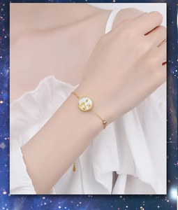 Close-up of a 925 sterling silver gold-plated bracelet with white shell cat pendant