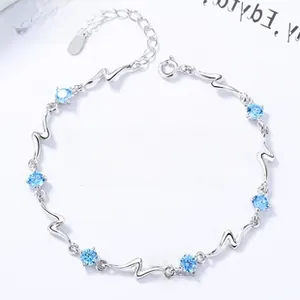 Macro detail of S925 silver bracelet featuring blue crystals and heart tag