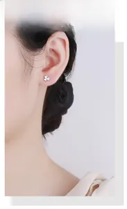 Close-up of minimalist S925 silver clover stud earring worn on a model's ear lobe