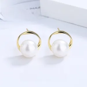 Détail de boucles d'oreilles anneaux dorés torsadés avec perle blanche sur carte