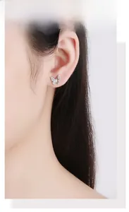 Close-up of a sterling silver butterfly stud earring with white zircon on a model