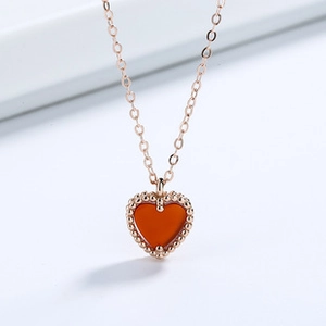 Macro shot of rose gold heart pendant with red agate stone and beaded edge detail
