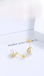 Gros plan détaillé de boucles d'oreilles en perles de nacre blanches sur base dorée