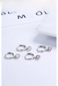 Macro shot of S925 silver heart earrings with pink and white cat eye stone pendants