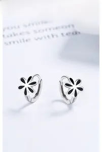 Détail macro de créoles en argent 925 avec pendentifs fleurs en émail noir