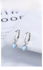 Macro view of S925 silver heart earrings with blue moonstone on a white display