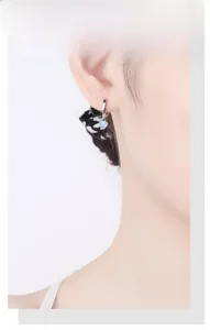 Detail shot of s925 silver heart earring with pale pink cat eye stone on female ear