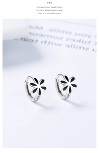 Détail de boucles d'oreilles créoles fleurs noires en argent 925 sur fond blanc chic