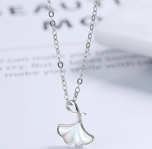 Vue macro du collier feuille de ginkgo en argent avec incrustation de nacre blanche polie