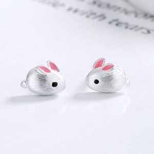Close-up of S925 sterling silver rabbit stud earrings with pink enamel ears on white surface