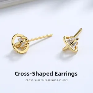 Macro shot of gold cross-shaped stud earrings with sparkling circular center stones