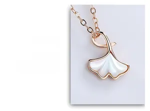 Vue macro du pendentif feuille de ginkgo en or rose avec incrustation de nacre