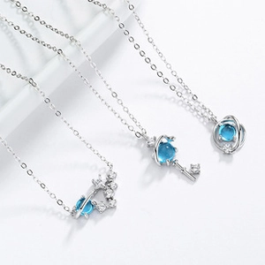 Detail of 925 silver planet, heart, and key necklaces with blue zircon stones