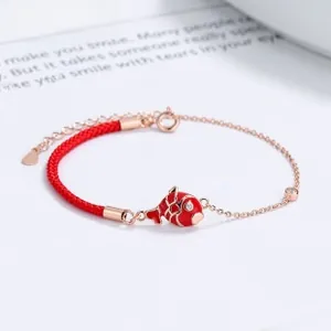 Detail of red koi fish charm bracelet with rose gold chain and braided cord