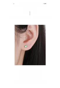 Detail of a 925 sterling silver rectangular emerald green stud earring worn on ear