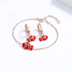 Detail of red enamel fish jewelry set with rose gold chain bracelet and hoop earrings