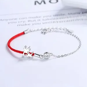 Close-up of 925 silver bracelet with red cord and hollow calf pendant with white zircon