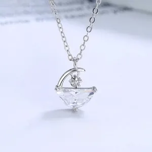 Macro shot of silver crescent moon pendant with clear water-drop crystal on a thin chain