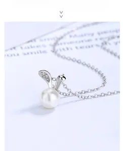 Detail of silver bunny rabbit ears with sparkling zircons and a round white pearl pendant