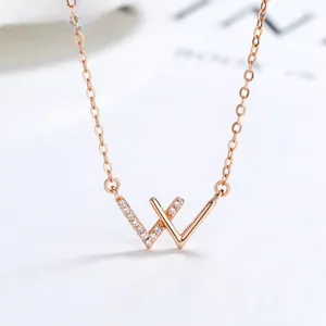 Gros plan du pendentif en forme de W or rose serti de diamants sur chaîne fine